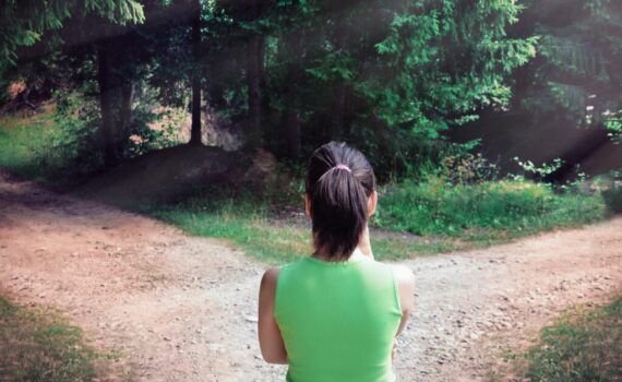 Woman standing at a fork in a forest path, symbolizing the decision between passive and nonpassive real estate activities for tax purposes.
