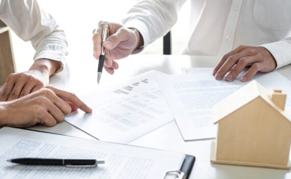Two real estate professionals reviewing property and time-tracking documents to determine material participation hours for tax reporting