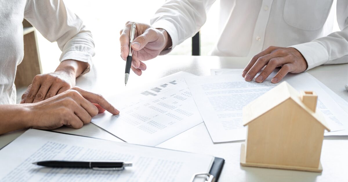Two real estate professionals reviewing property and time-tracking documents to determine material participation hours for tax reporting