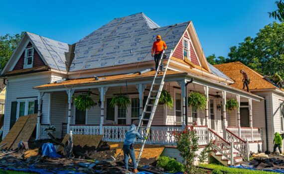 Construction crew replacing a residential roof, illustrating a partial asset disposition where old building components are removed and replaced during a property improvement project for real estate investors.