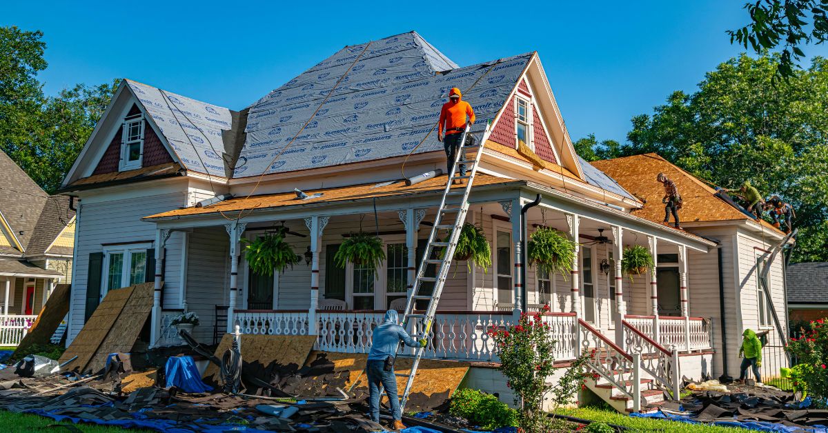 Construction crew replacing a residential roof, illustrating a partial asset disposition where old building components are removed and replaced during a property improvement project for real estate investors.