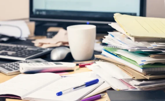 Messy desk with paperwork and notebooks, representing common tax and bookkeeping mistakes real estate investors make